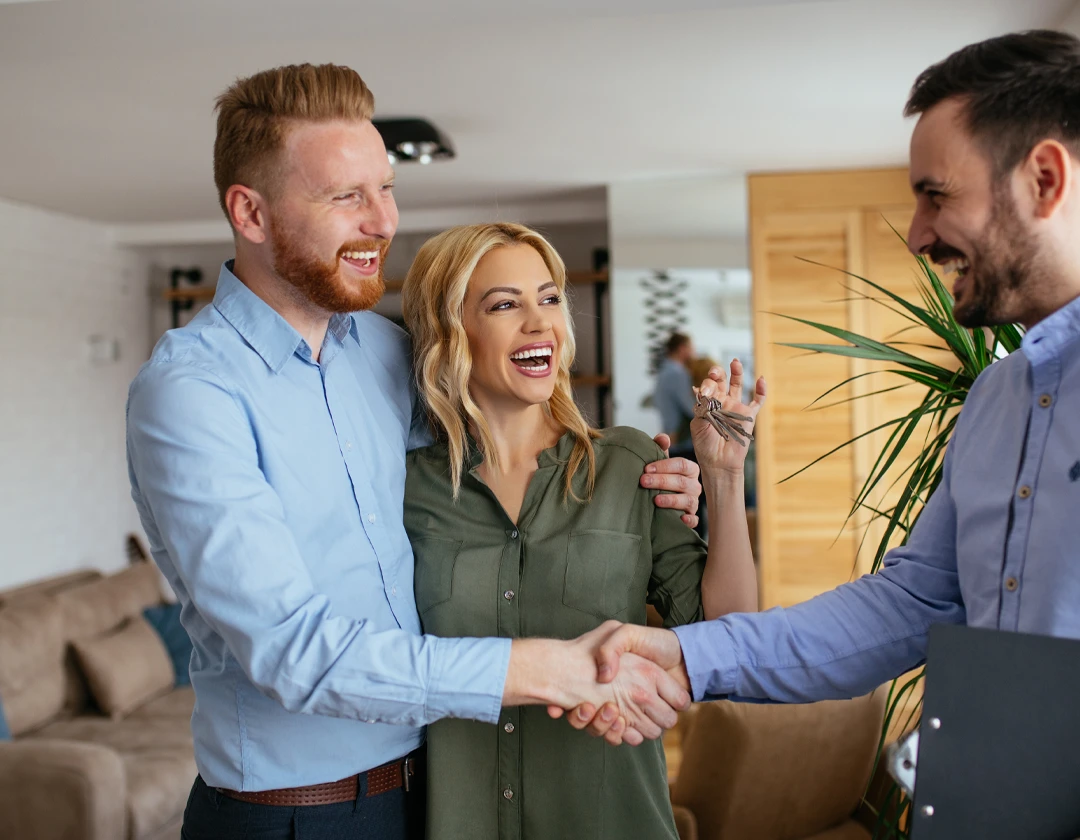 Happy couple shaking hands with a real estate agent after closing on a new home