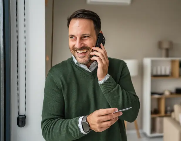 A happy homeowner on the phone, finalizing payment for the claim on the repair.