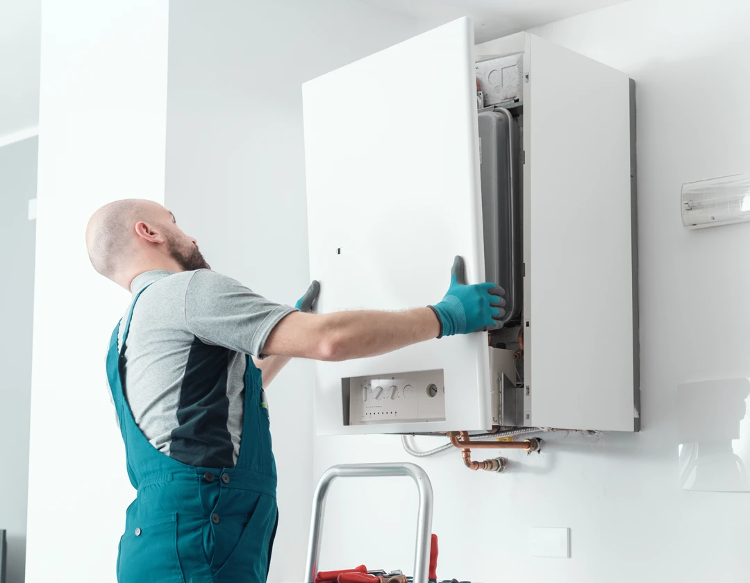 Technician servicing a wall-mounted boiler in a home