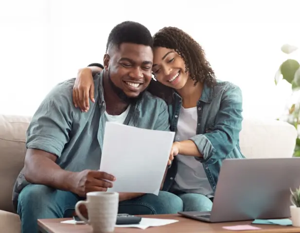 A couple sitting on a couch, looking over their APHW home warranty.