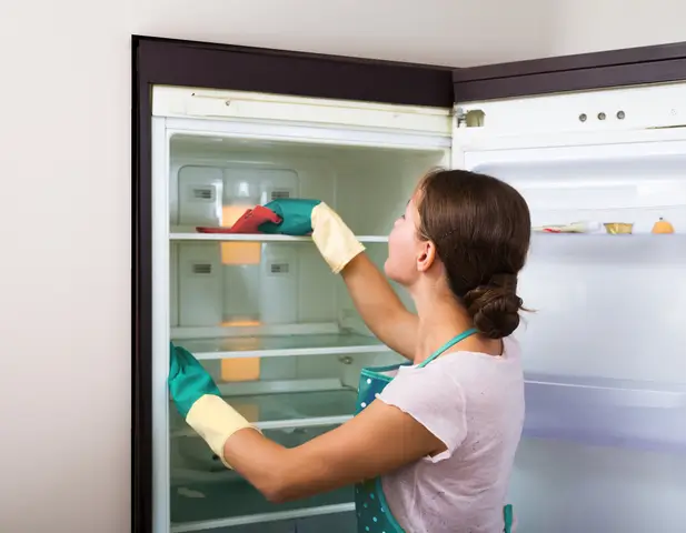 Homeowner carrying out routine maintenance on her refrigerator.