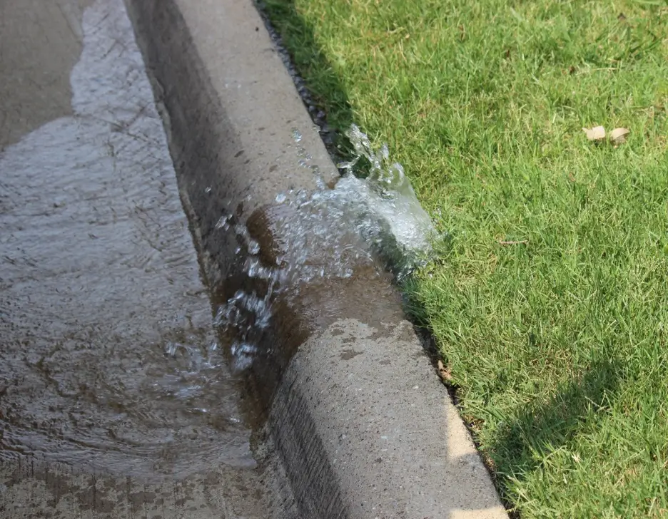 A water leak between a curb and lawn.