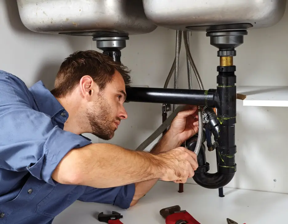 A man repairing bathroom plumbing.