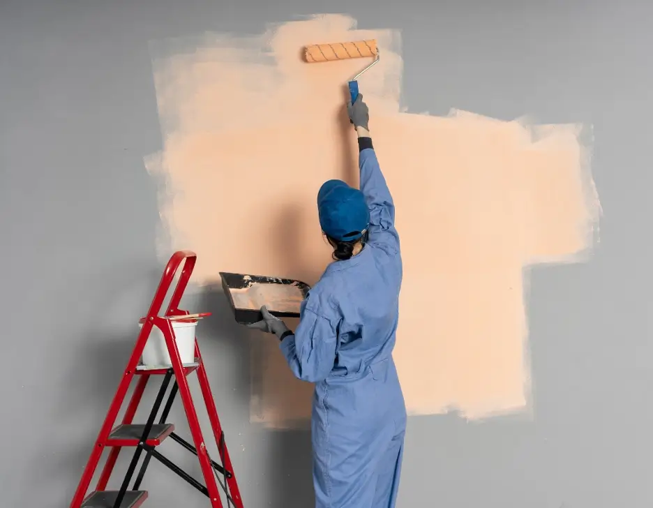 A professional painter painting a large wall inside of a home.