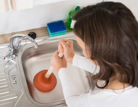 A woman plunging her sink.