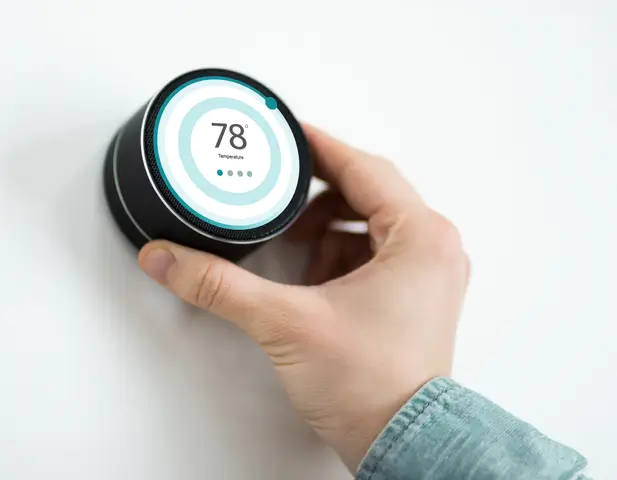 Someone adjusting a smart thermostat.