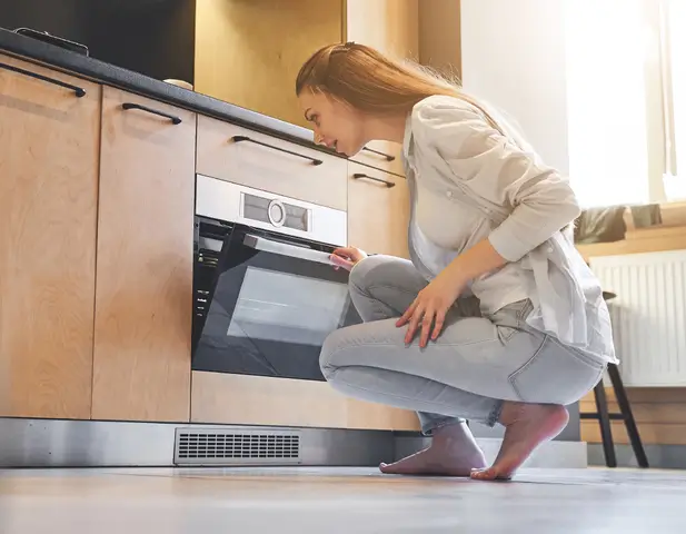 Woman inspecting oven.