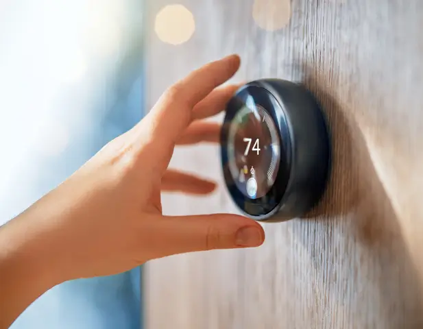 Someone adjusting the temperature on a smart thermostat.