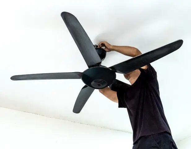 A homeowner changing the direction of his fan blades, and, as a result, lowering his energy bills and maintaining energy efficiency throughout the season.