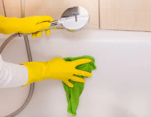 Someone rinsing the inside of their bathtub with their shower head.
