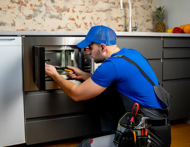 A maintenance man repairing a built-in microwave.