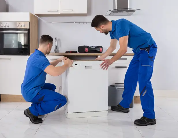 Two maintenance men installing a new dishwasher in the kitchen.