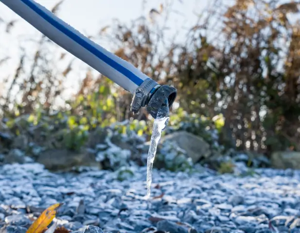 A hose pipe that has frozen water flowing through it.